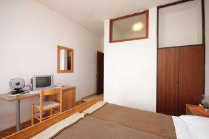 a bedroom with a bed and a desk with a television at Twin Room Luka 8132e in Žman