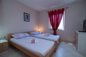 two beds in a bedroom with a red curtain at Apartments with a parking space Punta kriza, Cres - 8082 in Punta Križa