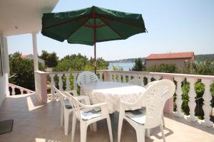 einen Tisch und Stühle auf einem Balkon mit Sonnenschirm in der Unterkunft Apartments by the sea Verunic, Dugi otok - 8104 in Veli Rat