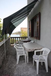 eine Terrasse mit einem Tisch und Stühlen auf dem Balkon in der Unterkunft Apartments by the sea Zaglav, Dugi otok - 8134 in Sali