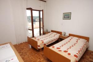 um quarto com duas camas e uma porta para uma varanda em Rooms by the sea Luka, Dugi otok - 8132 em Žman