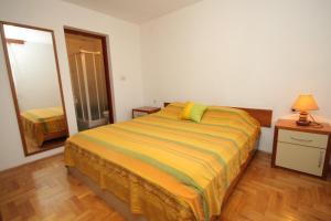 a bedroom with a bed with a yellow and green blanket at Apartment Mali Losinj 8090c in Mali Lošinj