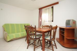 a living room with a table and chairs and a couch at Apartment Mali Losinj 8090c in Mali Lošinj