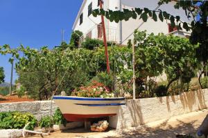a boat sitting in a garden next to a house at Apartments by the sea Sali, Dugi otok - 8110 in Sali