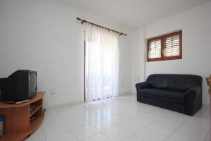 a living room with a couch and a television at Apartments by the sea Sali, Dugi otok - 8121 in Sali