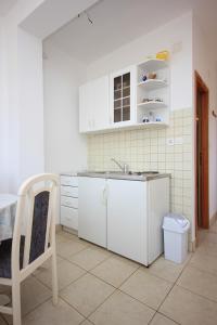 a white kitchen with a sink and a chair at Apartments by the sea Sali, Dugi otok - 8121 in Sali