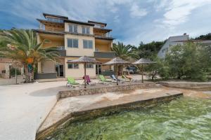 ein Haus mit Stühlen und Sonnenschirmen sowie einem Pool in der Unterkunft Apartments by the sea Savar, Dugi otok - 8128 in Brbinj