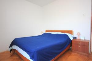 a bedroom with a blue bed and a night stand at Apartments by the sea Savar, Dugi otok - 8080 in Brbinj