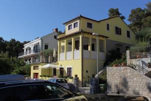 a yellow house with cars parked in front of it at Apartments by the sea Mali Losinj (Losinj) - 8093 in Mali Lošinj