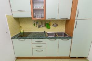 a small kitchen with white cabinets and a sink at Apartment Mali Losinj 8093b in Mali Lošinj