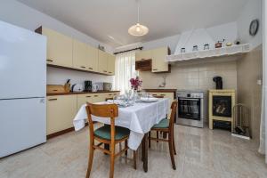 eine Küche mit einem Tisch mit Stühlen und einem weißen Kühlschrank in der Unterkunft Holiday house with a parking space Veli Rat, Dugi otok - 8096 in Veli Rat