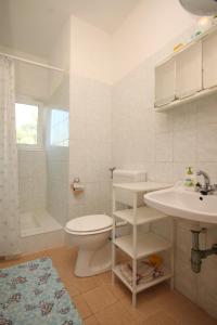 a white bathroom with a toilet and a sink at Apartments by the sea Luka, Dugi otok - 8151 in Luka