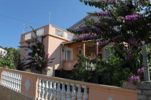 dom z białym płotem i fioletowymi kwiatami w obiekcie Apartments with a parking space Sali, Dugi otok - 8153 w mieście Sali