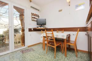 a dining room with a table and chairs and a tv at Family friendly apartments with a swimming pool Okrug Donji, Ciovo - 8072 in Okrug Donji