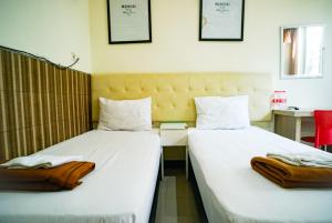 dwa łóżka siedzące obok siebie w pokoju w obiekcie Hoki Homestay Mitra RedDoorz near Rumah Sakit Dr Soetomo Surabaya w mieście Karangmendjangan