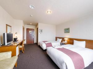 a hotel room with two beds and a desk at Tabist Abashiri Central Hotel in Abashiri
