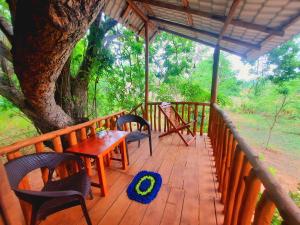 una terraza de madera con mesa, sillas y un árbol en La Casa Safari Resort en Udawalawe