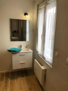ein Bad mit einem Waschbecken, einem Spiegel und einem Fenster in der Unterkunft AlloAppartMeuble StPol in Saint-Pol-sur-Ternoise