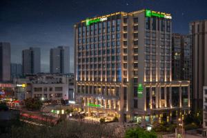 een hoog gebouw met 's nachts lichten erop bij Holiday Inn Express Chengdu Huanhuaxi, an IHG Hotel in Chengdu
