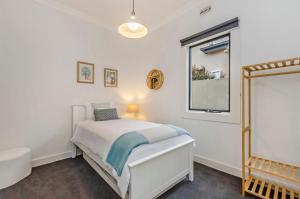 a white bedroom with a bed and a window at Dianas Place in Warrnambool