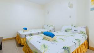 two beds in a room with white walls at Golden Sunrise Hotel I by RedDoorz in Batikbatik