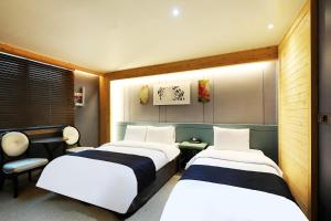 Habitación con 2 camas y silla en Buan Tourist Hotel en Buan