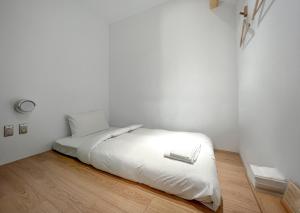białe łóżko w białym pokoju z drewnianą podłogą w obiekcie 山鄰山林青年文旅 forest 3030 hostel w mieście Yuli