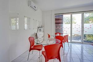 uma sala de jantar com uma mesa de vidro e cadeiras vermelhas em OYO LIFE 91594 Bungah Residence Syariah em Gresik