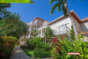 a building with a palm tree in front of it at Lawson Rock - Seahorse 105 condo in Roatan