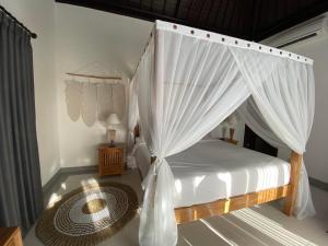 a bedroom with a canopy bed with white curtains at The Palms Canggu in Canggu