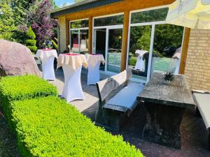 un patio con mesas, sillas y una sombrilla en Waldhotel en Boizenburg