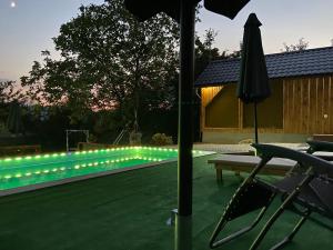 a pool with a string of lights next to a table and an umbrella at Hellena in Sarajevo