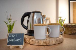 a tea kettle and two cups on a wooden board at Agritur Maso Librar in Trento