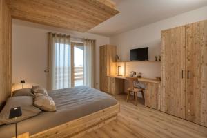 a bedroom with a bed and a desk with a television at Agritur Maso Librar in Trento