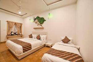 two beds in a room with white walls and wooden floors at The Bheemgarh in Jaisalmer