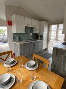 a kitchen with a wooden table with plates and wine glasses at Augusta lodge in Wisbech