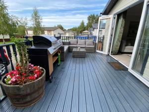 a deck with a grill and a couch on a porch at Augusta lodge in Wisbech