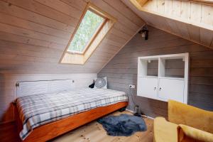Schlafzimmer im Dachgeschoss mit einem Bett und einem Fenster in der Unterkunft White & Black in Kołczewo
