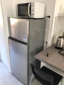a stainless steel refrigerator with a microwave on top of it at Apartman Valinor in Miholašćica