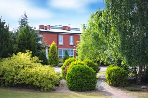 a red brick house with bushes in front of it at Hotel Manhatan in Zygry