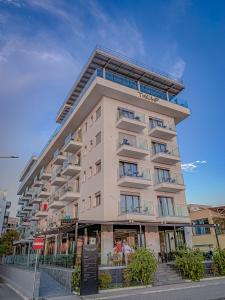 un edificio de apartamentos alto en una calle de la ciudad en Hotel Bar Restaurant Triumf Shengjin en Shëngjin