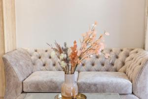 un jarrón con flores en una mesa delante de un sofá en AGORA luxury BOUTIQUE HOTEL, en Loutraki