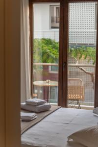 1 Schlafzimmer mit einem Bett und einem Balkon mit einem Tisch in der Unterkunft AGORA luxury BOUTIQUE HOTEL in Loutraki