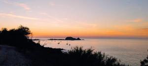 un tramonto sull'oceano con barche in acqua di Maison duplex 2 chambres, avec jardin, 800m plage a Belgodère
