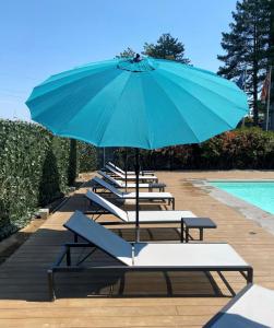 - une rangée de chaises longues avec un parasol à côté de la piscine dans l'établissement Belstay Milano Assago, à Assago