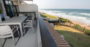 a balcony with a table and chairs and the beach at 8 Bronze Beach Umhlanga Rocks in Durban