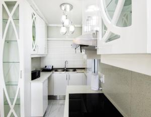 a white kitchen with white cabinets and a sink at 8 Bronze Beach Umhlanga Rocks in Durban