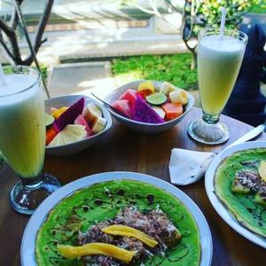a wooden table topped with plates of food and drinks at Sudiana House in Ubud