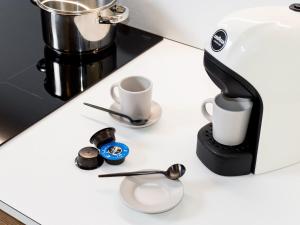 a coffee maker on a counter with cups and spoons at Cally Suite Room in Martina Franca