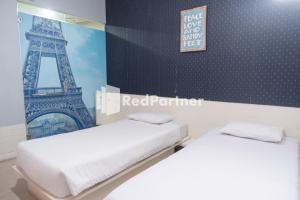 duas camas num quarto com a torre Eiffel em Londres Bed and Breakfast RedPartner near Gembira Loka Zoo em Yogyakarta
